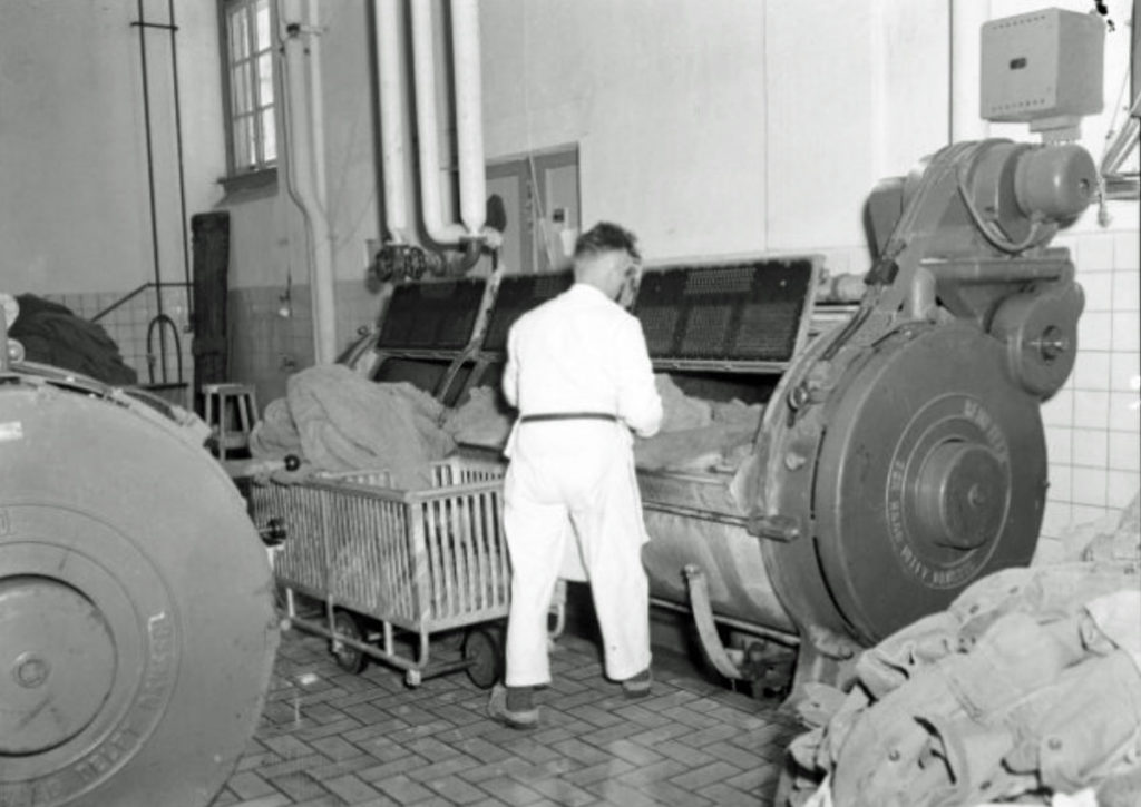Defensie-eiland Woerden - medewerker vult wasmachine Depot Retour Goederen te Woerden foto JC Enkelaar in 1954 Leger Film- en Fotodienst